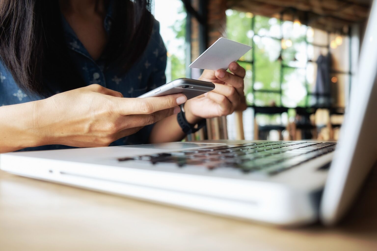 Mujer realizando pago digital con celular y tarjeta frente a laptop en Perú
